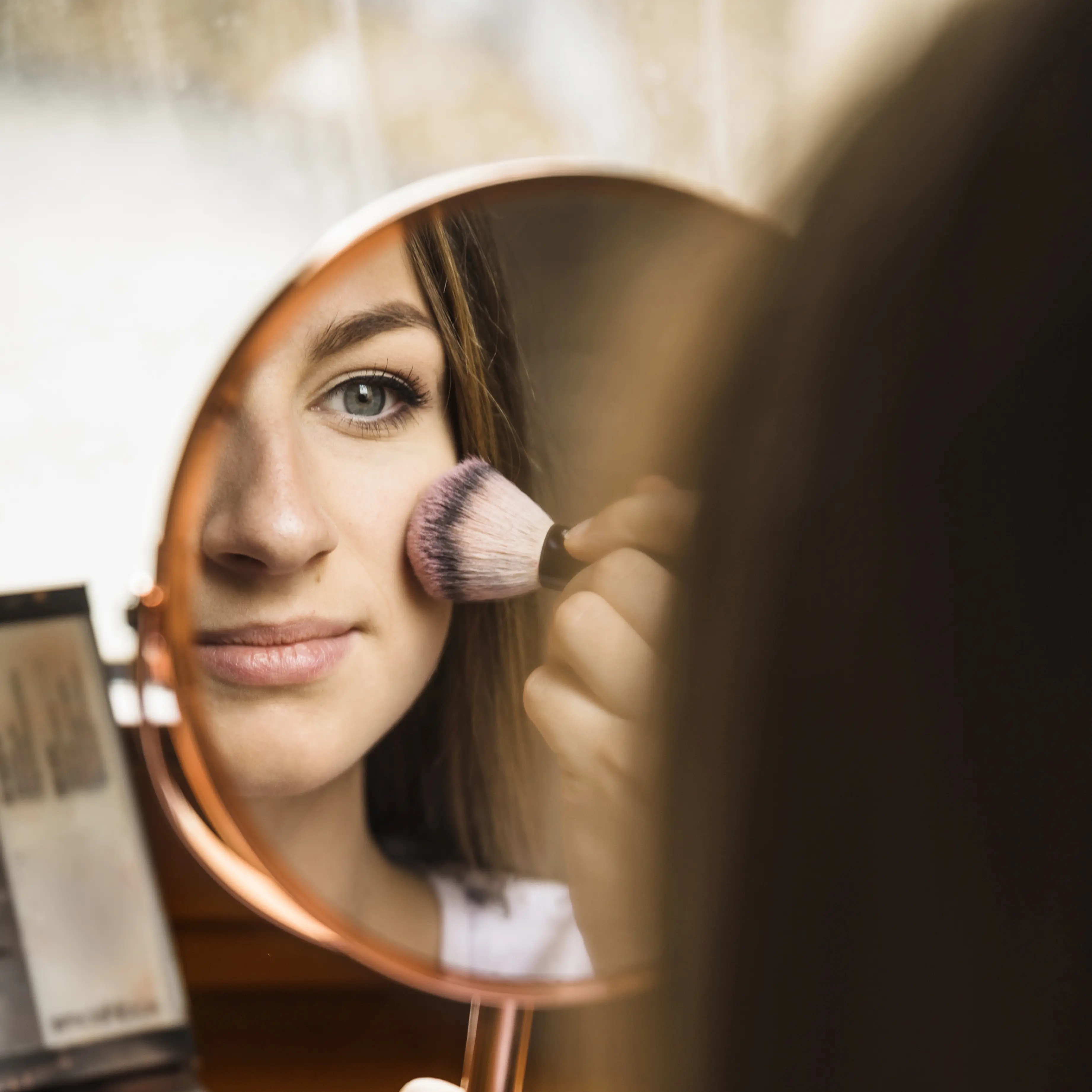espejo-de-mano-con-reflejo-de-mujer-aplicando-colorete-en-la-cara.jpg